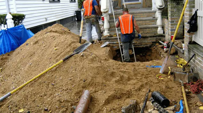 Contractors performing foundation protection and exterior drainage excavation near residential home steps in Milwaukee, WI